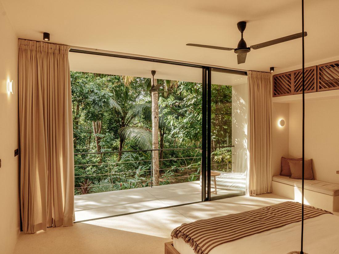 A villa bedroom in Ahangama with its curtains drawn back to the jungle