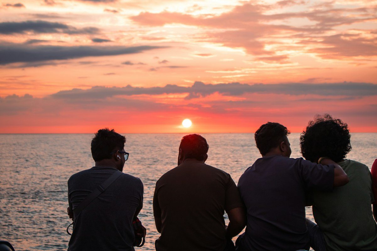 Four friends on a sea wall watching the sun go down