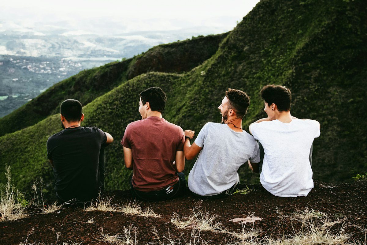 Four friends sitting on a green ridge, looking out over the valley