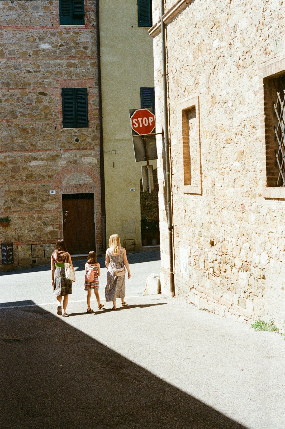 Two women walking down a sunlit stone lane