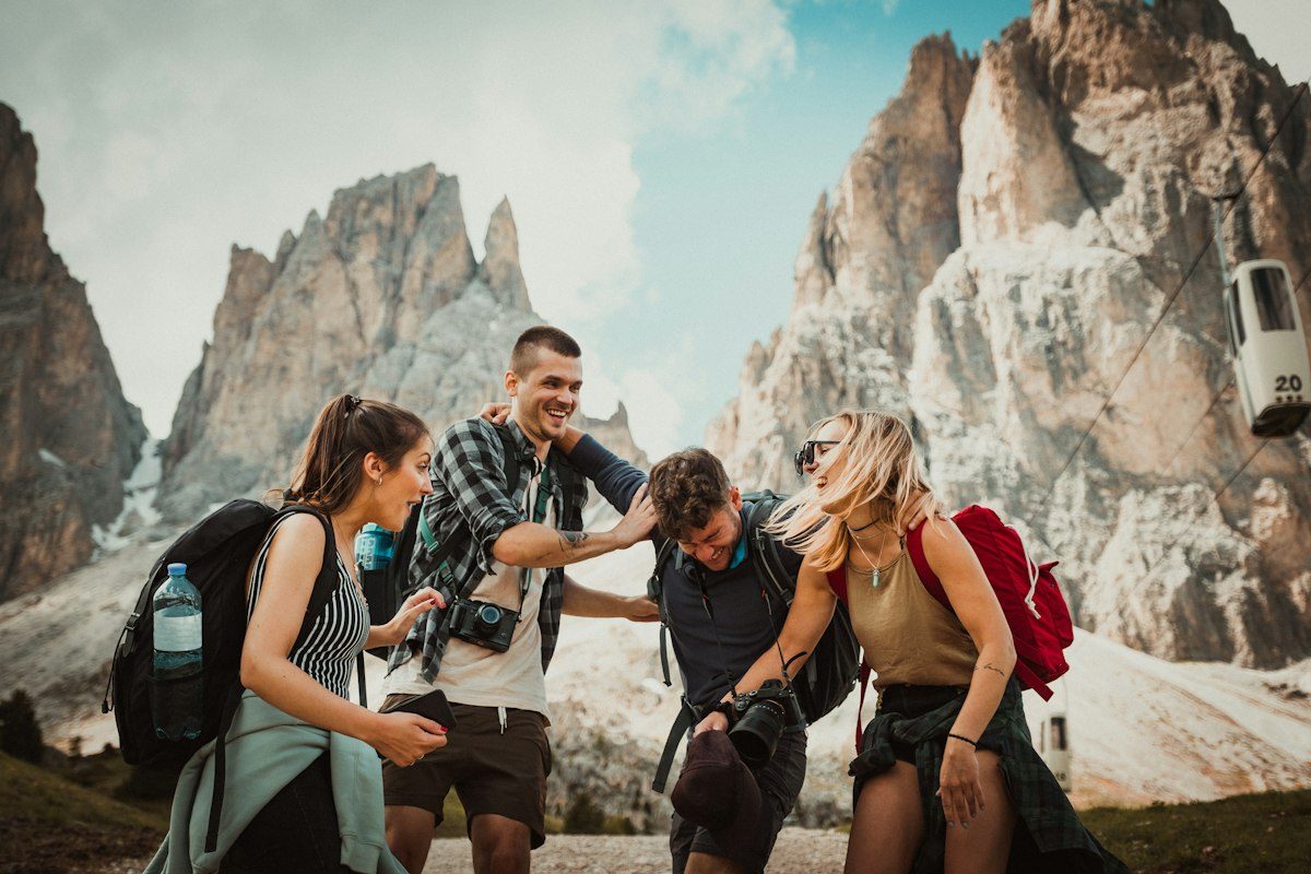 Four friends laughing on a trail below the Dolomites