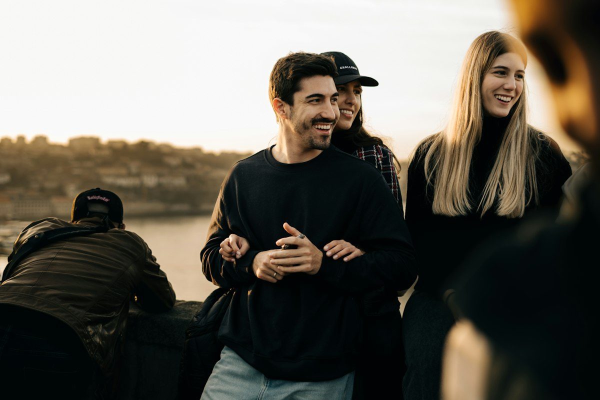 Friends standing together on a hill at dusk, laughing