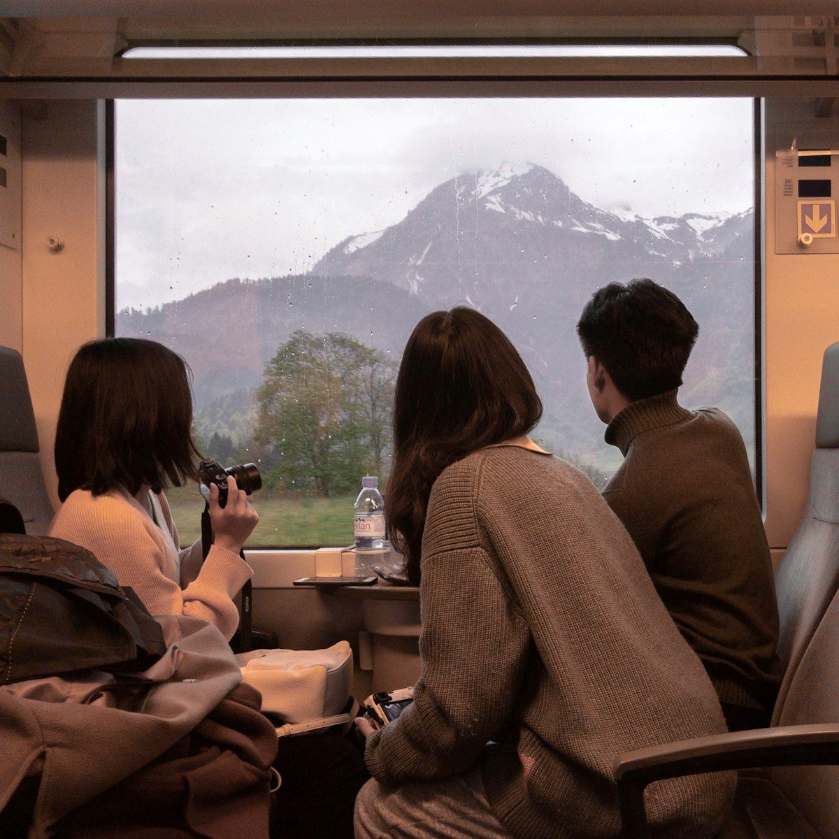Friends in a train carriage watching snowy mountains