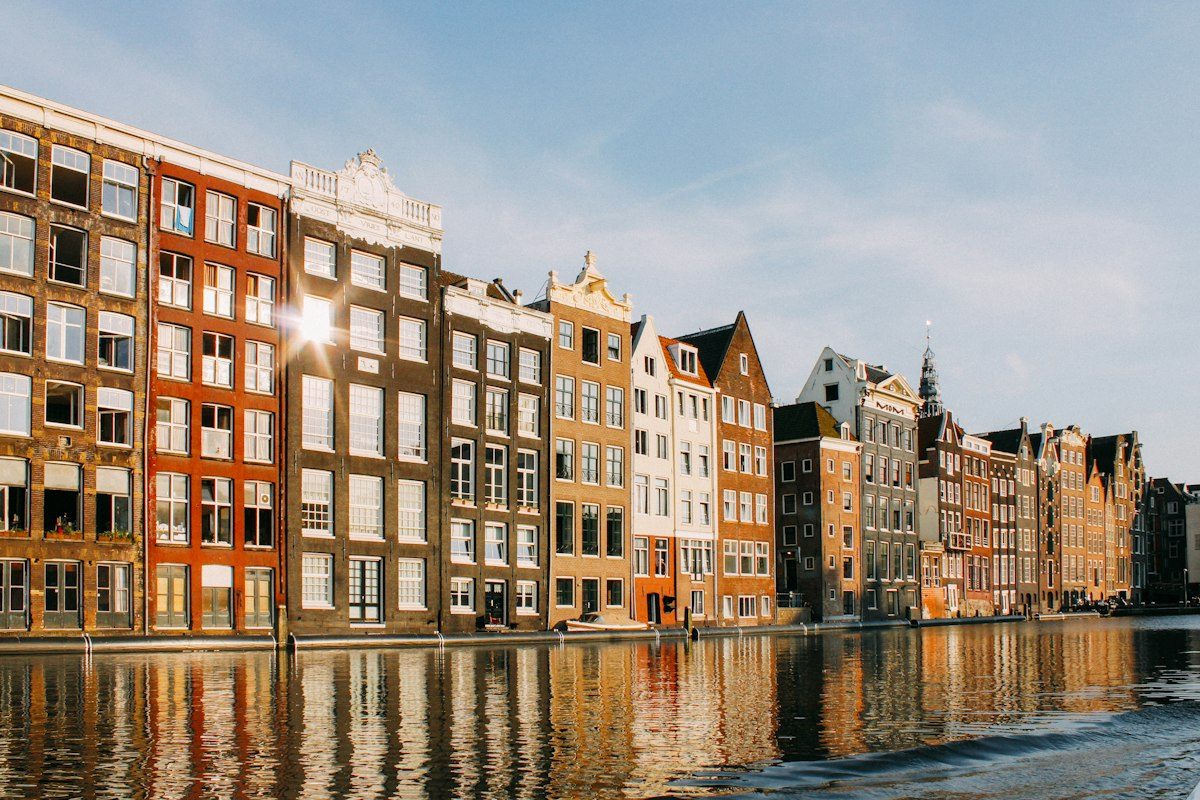 Tall canal houses in red, brown and white brick reflected in a canal in Amsterdam