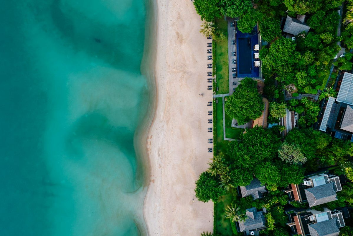 A white beach and turquoise water seen from above, with villas among the trees on Koh Samui