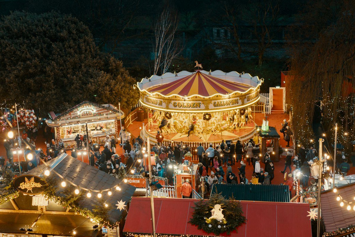 A carousel and stalls lit up at a Christmas market at night